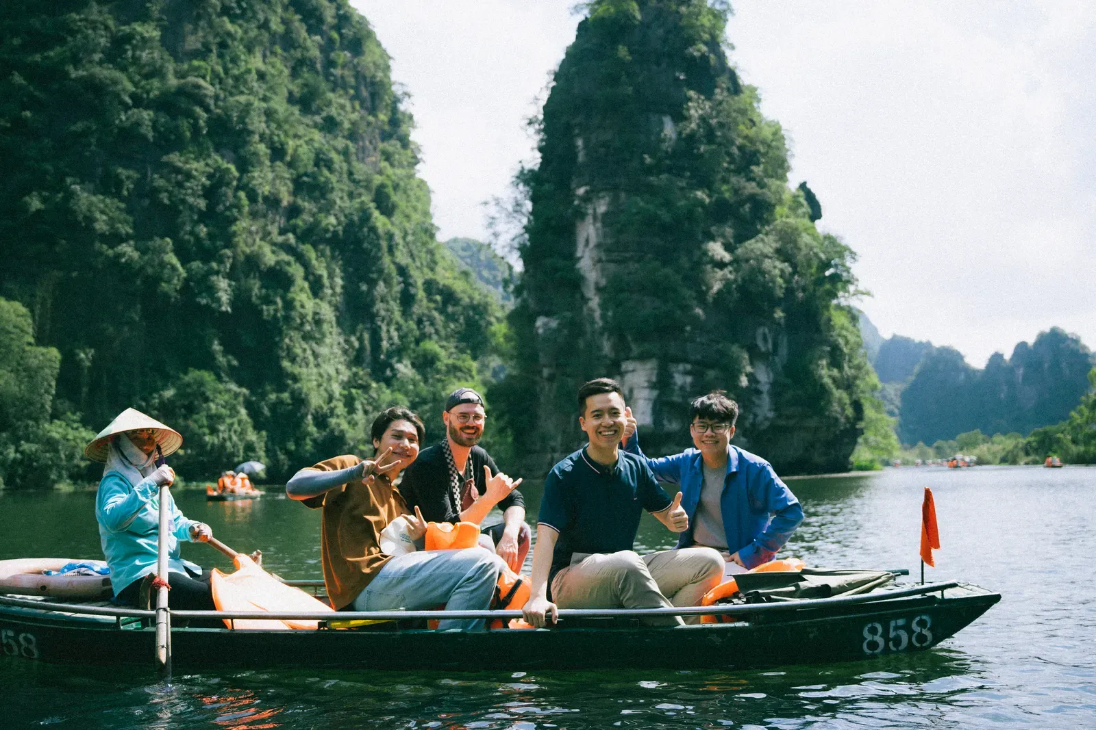 Travelers on a rowboat beneath limestone cliffs in Ninh Binh