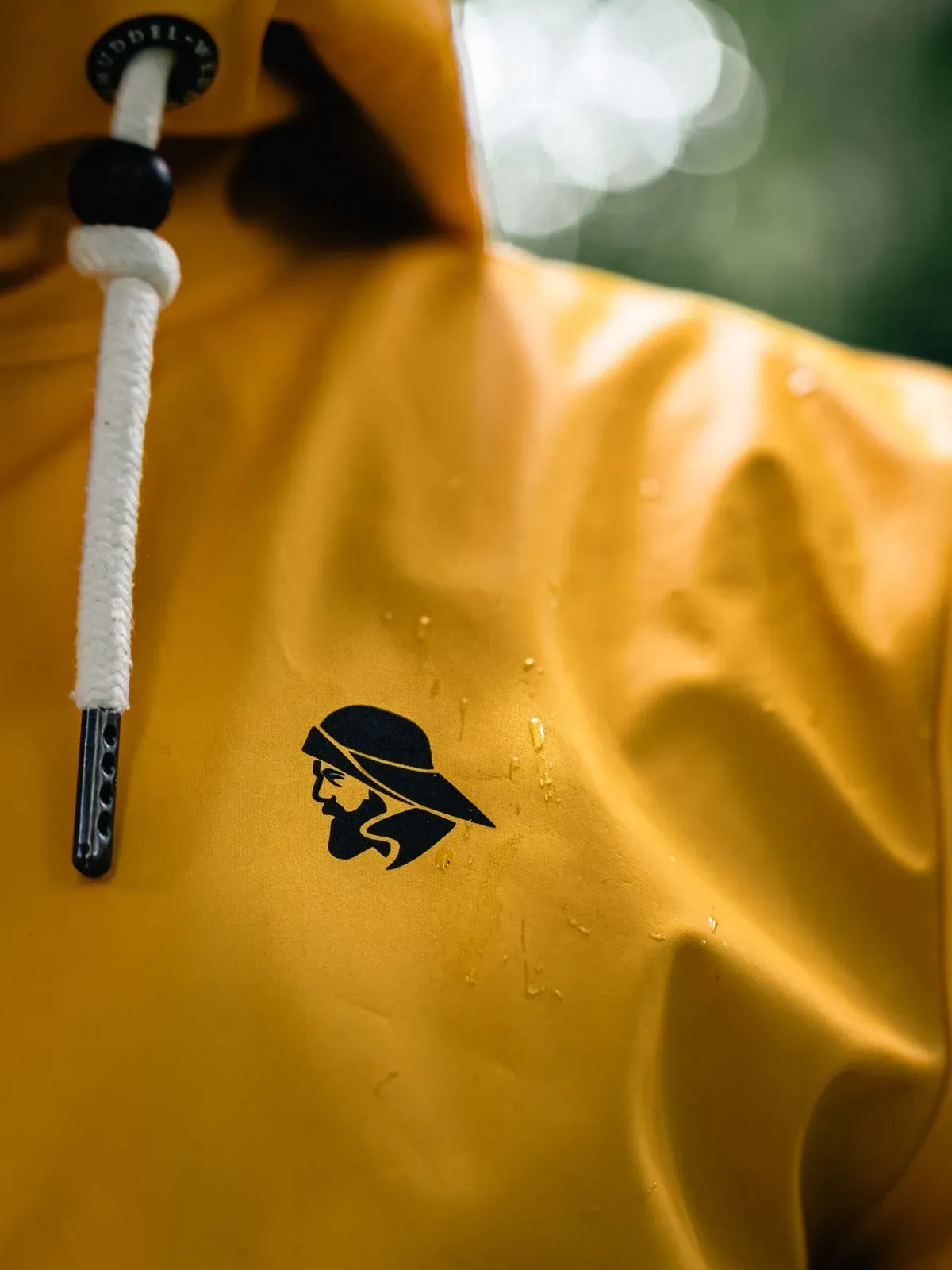 Close-up of a yellow rain jacket with raindrops