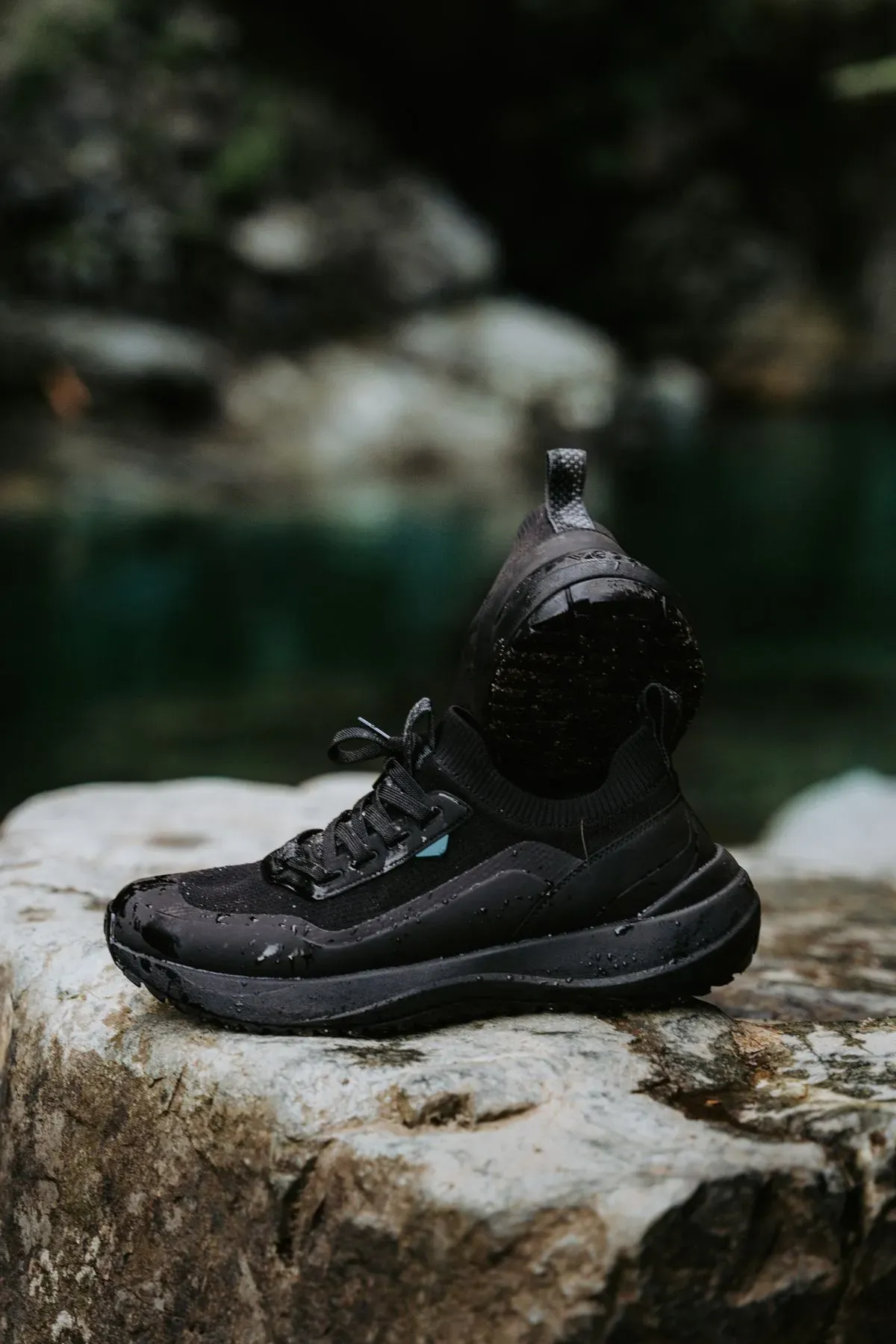 A walking shoe with water droplets on a rock