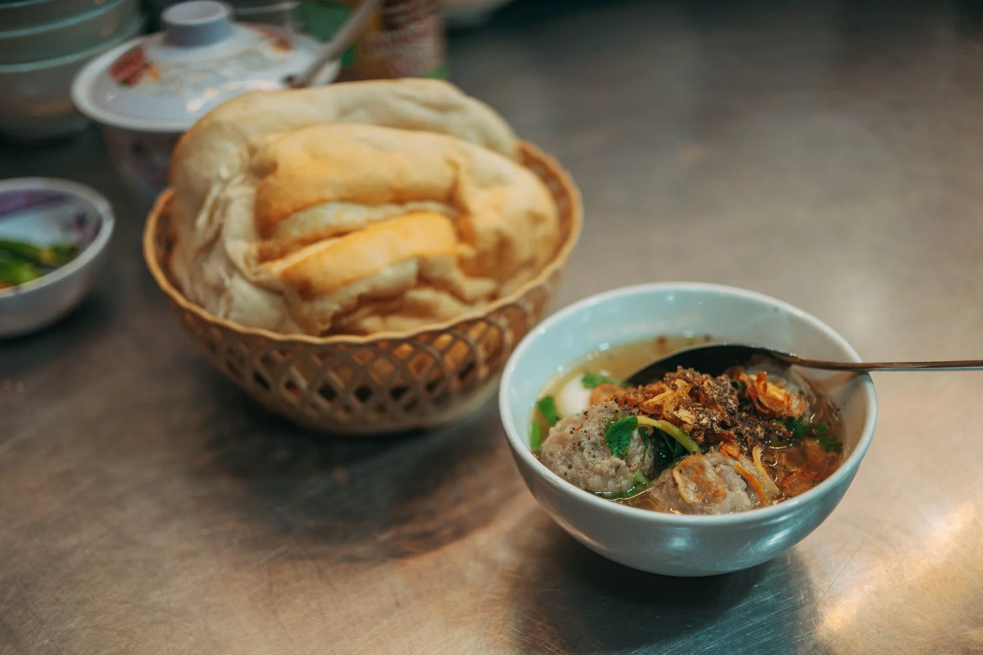 In Da Lat, banh mi xiu mai can arrive with the bread served separately. Da Lat banh mi xiu mai with a bread roll and a bowl of meatballs in broth